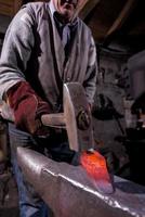 blacksmith manually forging the molten metal photo