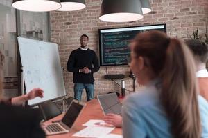 Leader give a business presentation at an office conference meeting, businessman coach mentor explains graph chart on board corporate group workshop training in boardroom. Selective focus photo