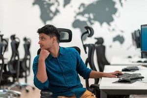 Casual business man working on desktop computer in modern open plan startup office interior. Selective focus photo