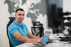 Young man sitting in office and working on desktop pc. Businessman looking at computer monitor while working in office. photo