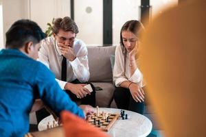 Multiethnic group of business people playing chess while having a break in relaxation area at modern startup office photo