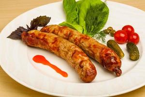 Grilled sausages on the plate and wooden background photo