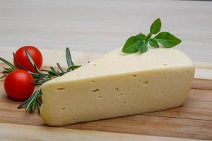 Yellow cheese on wooden board and wooden background photo