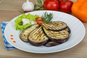 berenjena a la parrilla en el plato y fondo de madera foto