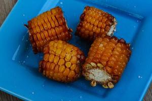 Grilled corn on the plate and wooden background photo