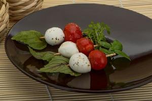 Caprese salad on the plate and wooden background photo