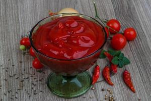ketchup de tomate en un recipiente sobre fondo de madera foto