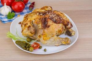 pollo a la parrilla en el plato y fondo de madera foto