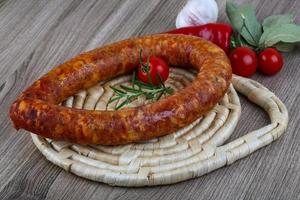 Sausage ring on wooden board and wooden background photo