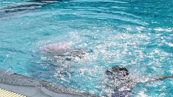 le sorelline felici giocano nella piscina all'aperto del resort tropicale durante le vacanze estive in famiglia. bambini che imparano a nuotare. attività estive salutari per bambini. video