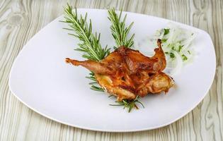 Grilled quail on the plate and wooden background photo