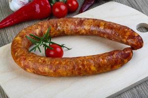 Sausage ring on wooden board and wooden background photo