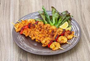 Prawn skewer on the plate and wooden background photo