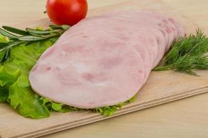 Sliced ham on wooden board and wooden background photo