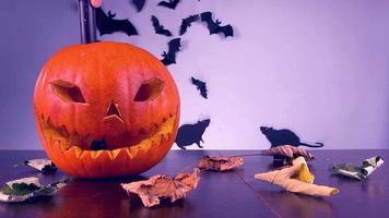 encendiendo calabaza con cara espeluznante, encienda la luz, fuego de la vela, exposición de Halloween en la mesa, murciélagos y ratones en el fondo video