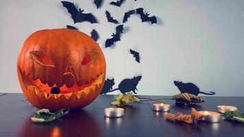 espeluznante decoración de halloween de terror en la mesa con calabaza aterradora. exposición de halloween en la mesa con calabaza, hojas en el viento y velas. video
