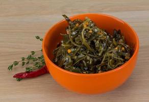 Laminaria salad in a bowl on wooden background photo