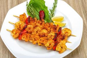 Prawn skewer on the plate and wooden background photo