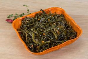 Laminaria salad in a bowl on wooden background photo