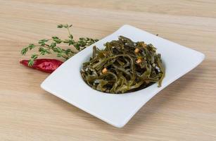 Laminaria salad in a bowl on wooden background photo