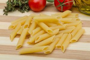 Raw penne on wooden board and wooden background photo