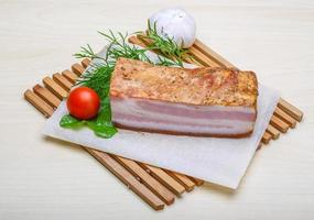 Raw bacon on wooden board and wooden background photo