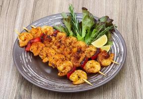 Prawn skewer on the plate and wooden background photo