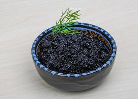 Black caviar in a bowl on wooden background photo