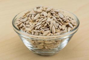 Sunflower seeds in a bowl on wooden background photo