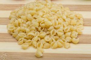 Shell pasta on wooden board and wooden background photo