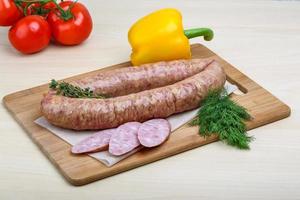 Smoked sausages on wooden board and white background photo