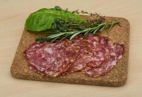 Salami on wooden board and wooden background photo