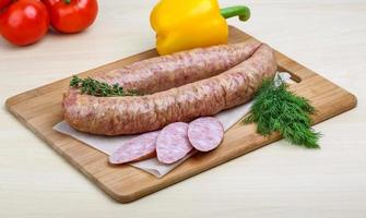 Smoked sausages on wooden board and white background photo