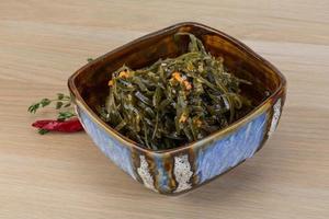 Laminaria salad in a bowl on wooden background photo