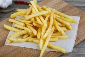 French fries on wooden board and wooden background photo