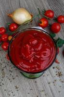 ketchup de tomate en un recipiente sobre fondo de madera foto