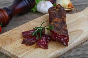 Salami sausage on wooden board and wooden background photo