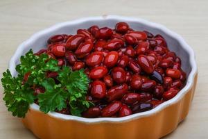 frijoles enlatados en un recipiente sobre fondo de madera foto