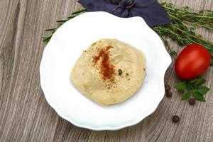 Hummus on the plate and wooden background photo