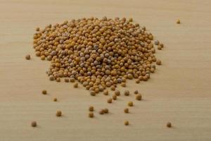 Mustard seeds on wooden background photo