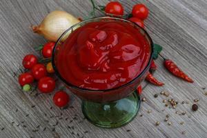 ketchup de tomate en un recipiente sobre fondo de madera foto