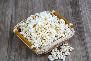 Popcorn in a basket on wooden background photo