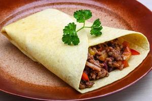 Burrito on the plate and wooden background photo