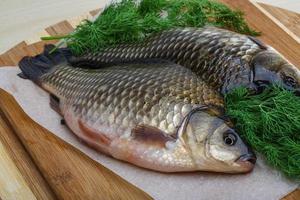 Two crucian on wooden board and wooden background photo