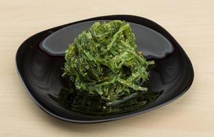 Chuka salad on the plate and wooden background photo