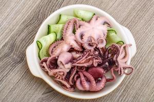 Marinated octopus in a bowl on wooden background photo