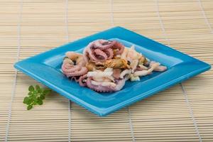 Seafood cocktail on the plate and wooden background photo