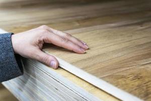 buyer's hand selects a thick sheet of laminated plywood in a store photo