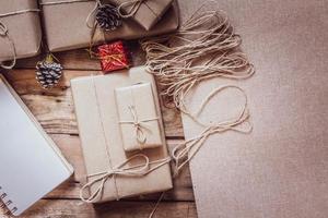 caja de regalo de navidad use papel reciclado marrón y un cuaderno y piñas en una mesa de madera. foto