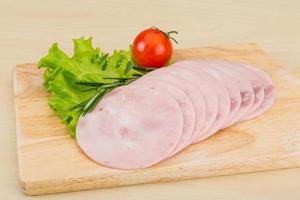 Sliced ham on wooden board and wooden background photo